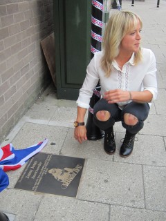 Jenny Jones squating near he  nearly unveiled plaque.