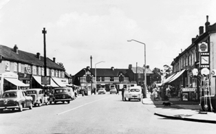 Old Black and white photo taken at the crossroads of Cleeve Hill, Badminton and Cleeve road, looking up Badminton road to the Horse Shoe Pub in the distance.