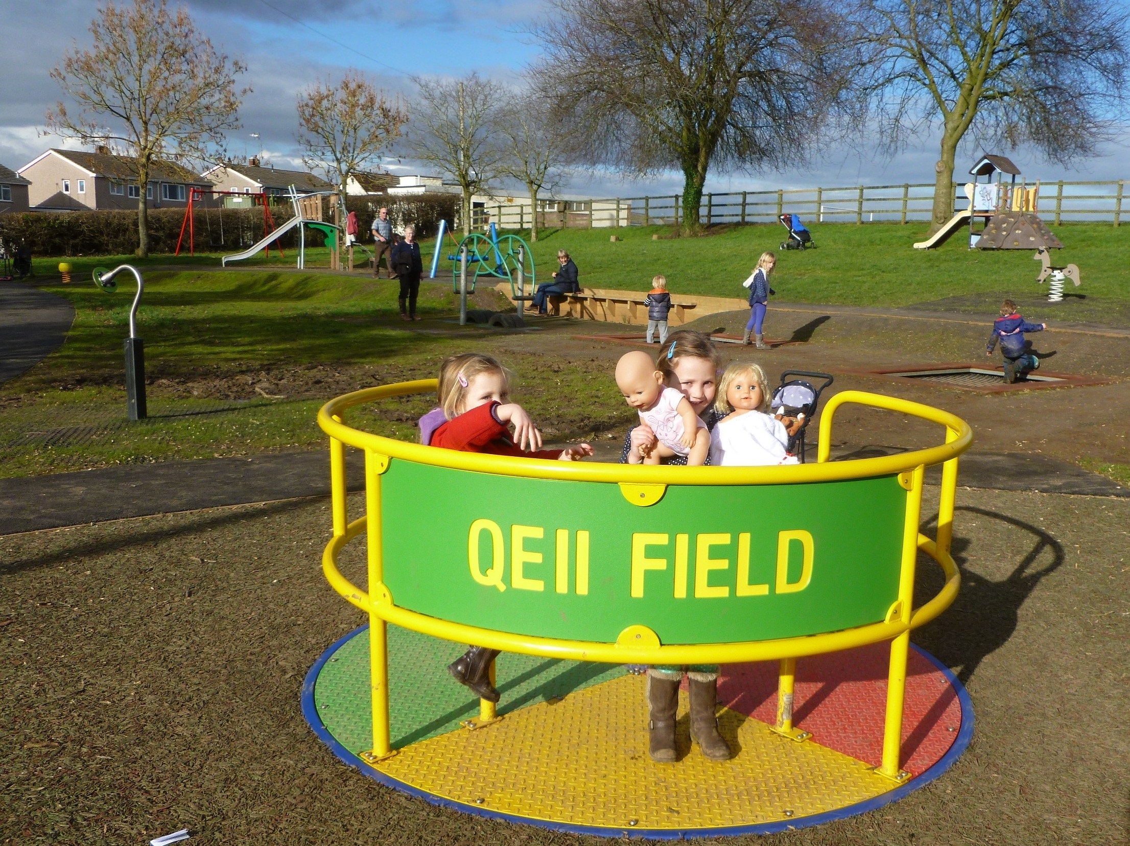 Children enjoying the Childrens roundabout, named QE 2 Field,  in the play area in King George the fifth park