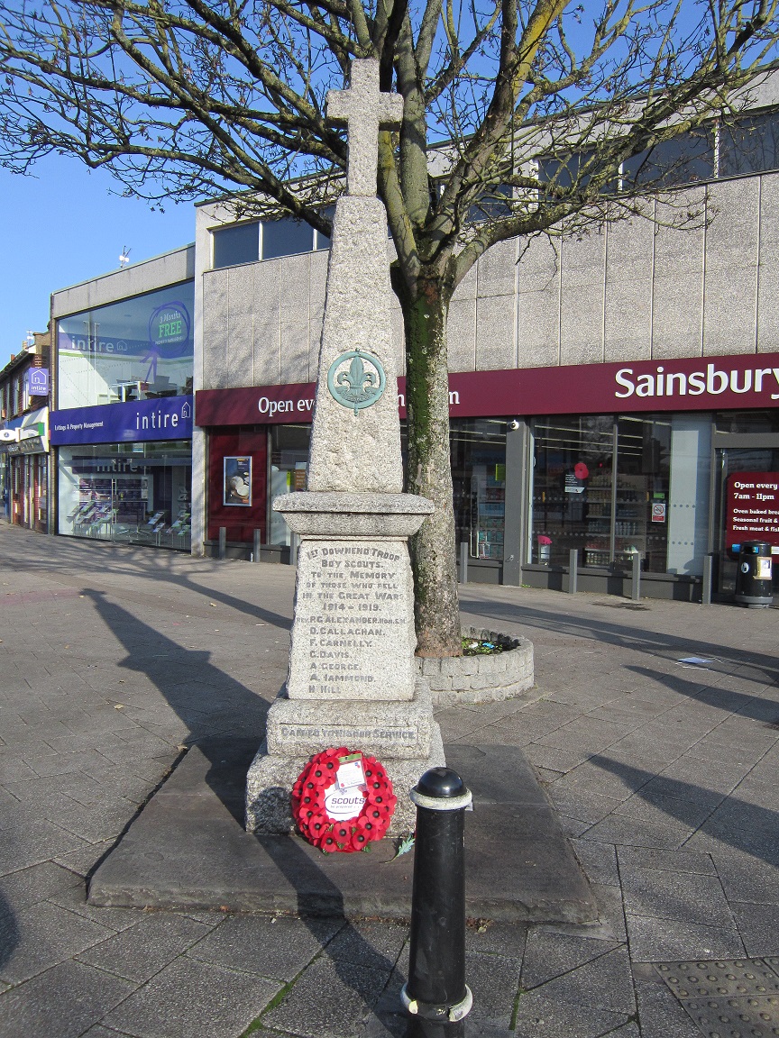 A colour photo of the Downend Scouts War Memorial with a poppy wreath at the foot of the memorial.